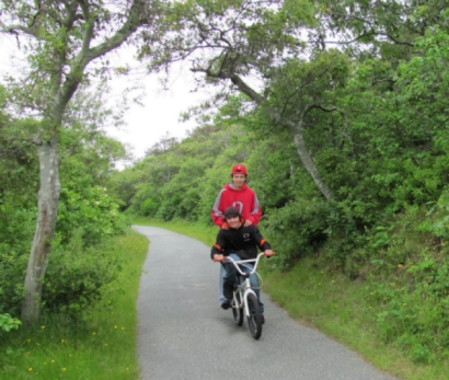 photos of tourists riding bikes along the Head of the Meadow Bike Trail with views of the Cape Cod sandunes and inlet marsh in the background
