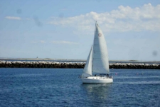photo of sailboat in the Cape Cod harbor with barrier wall in background