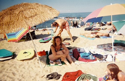 Photo showing a day at the beach with beach umbrellas and sunbathers at Head of the Meadow Beach