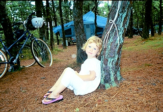 photo of young girl and her bike resting against the pine trees in her Cape Cod campsites at North of Highland Camping Area