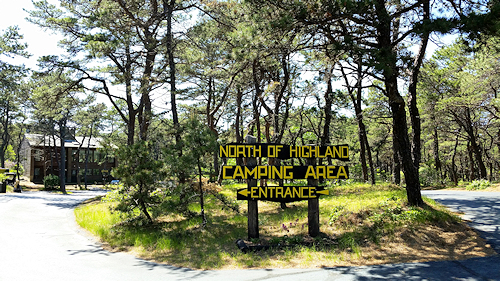 Sign in the pine trees pointing the entrance location for the Cape Cod campgrounds at North of Highland Camping Area with Head of the Meadow Road in the background